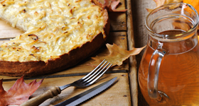 Zwiebelkuchen und etwas zu trinken sind auf einem Tisch serviert